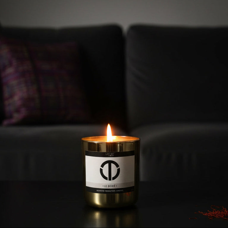 Candle with a logo on a dark surface in a dimly lit room