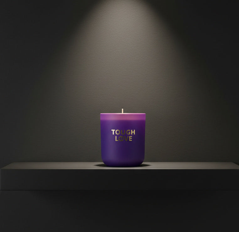 Purple candle with 'Tough Love' text on a dark background